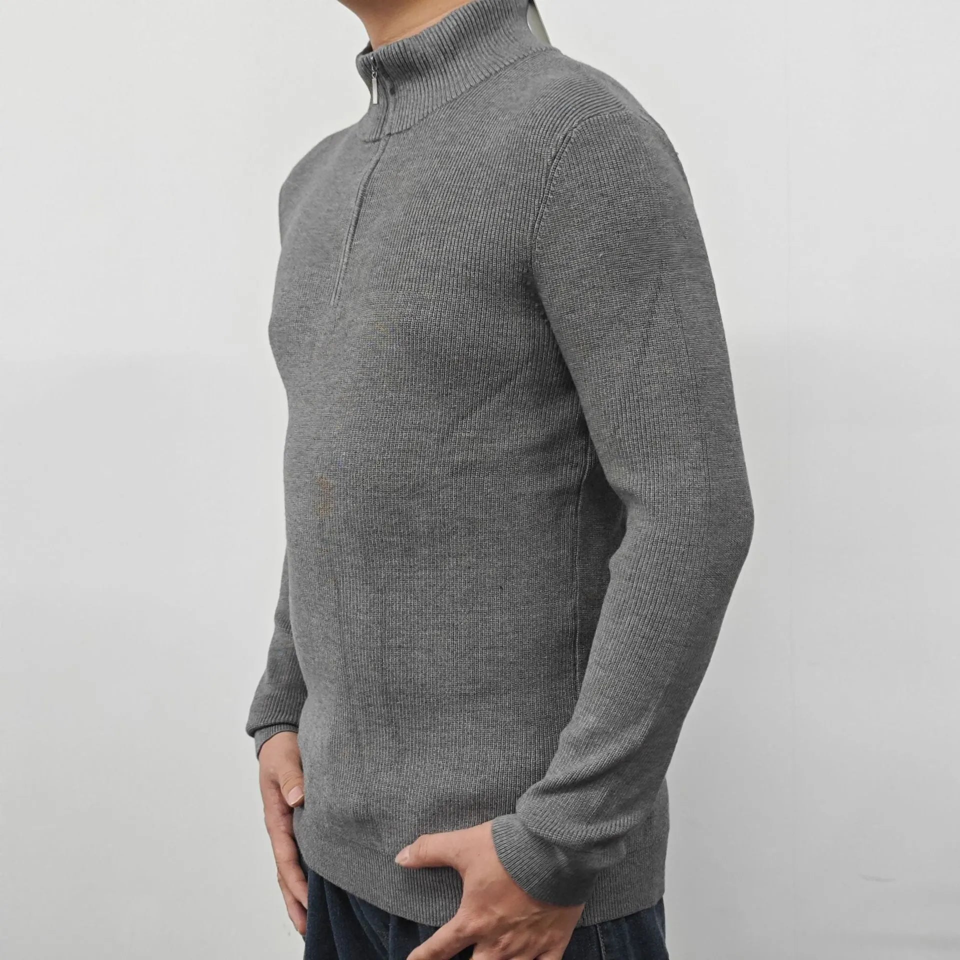 Man wearing a grey zip-up half-turtleneck sweater with long sleeves.