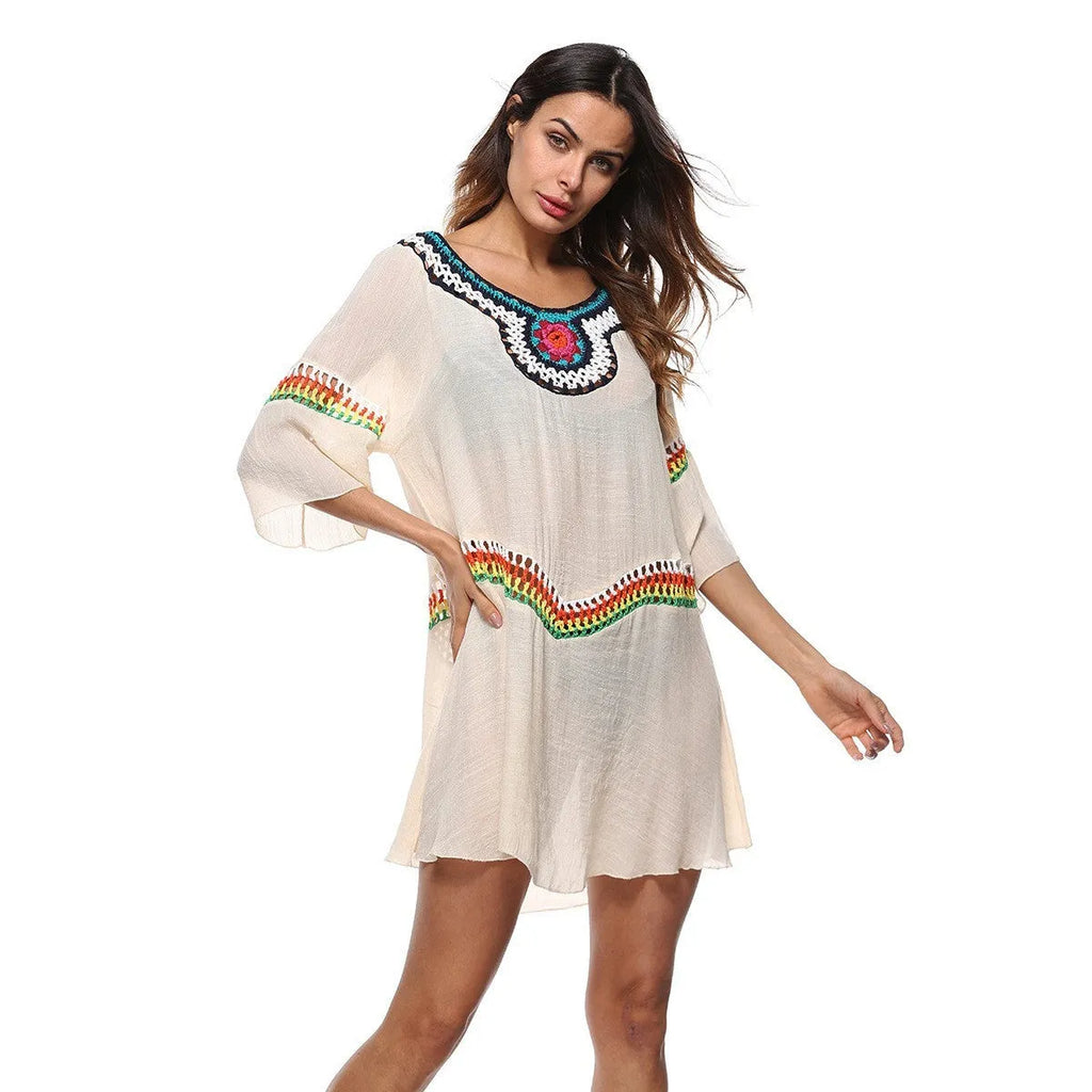 Female model wearing a crocheted ethnic style white sun protection cover-up on the beach.