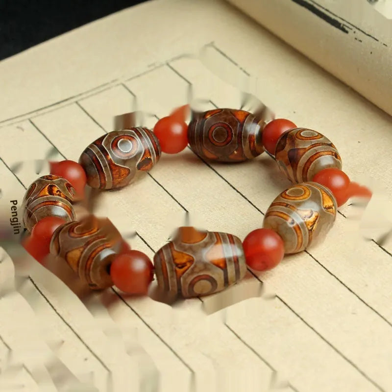 Distressed agate Tibetan bead bracelet with three-eye motifs and polished finish.