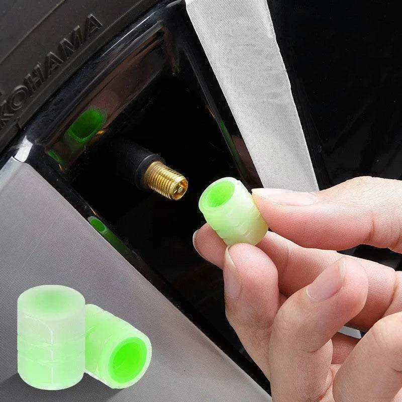 Set of four rubber luminous valve caps for car tyres on a dark background.