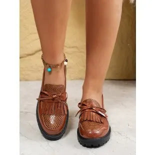 Women's brown artificial PU loafers with a black bow decoration on the vamp, shown on a white background.