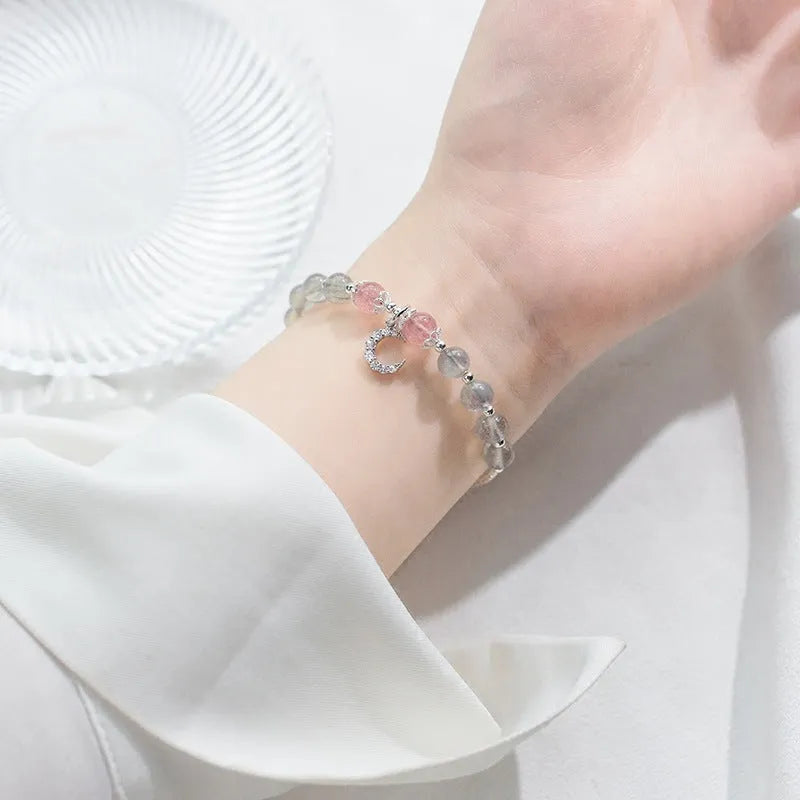 Handmade adjustable moonstone bracelet with silver crescent moon charm and crystal bead on a wrist.