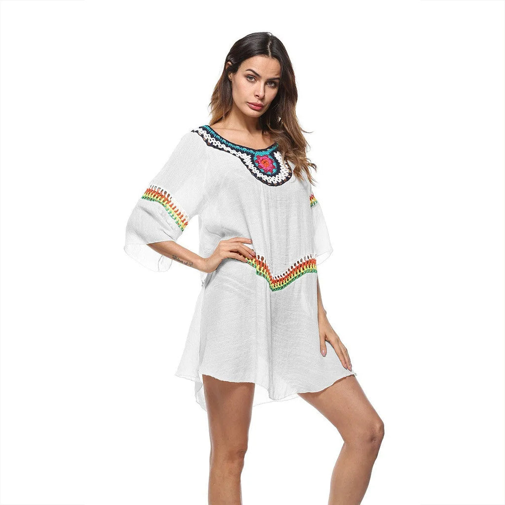 Female model wearing a crocheted ethnic style white sun protection cover-up on the beach.