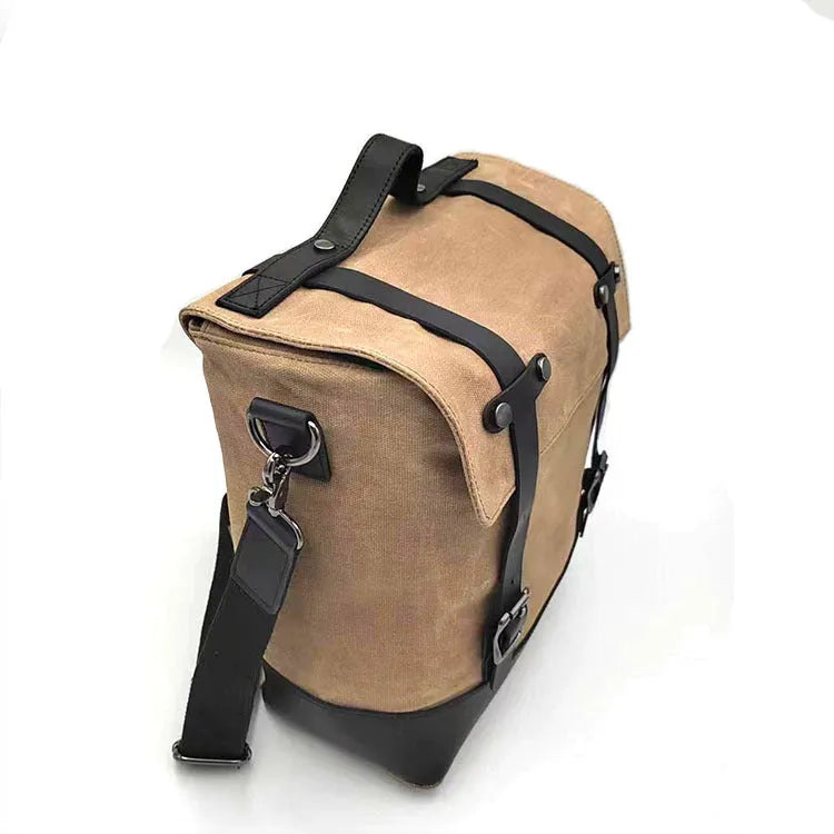 Black waterproof canvas motorcycle side pannier bag with cowhide detailing showing mounted position on bike