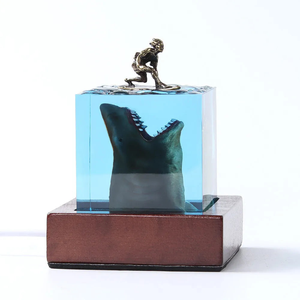 Clear epoxy resin ornament with shark surfing scene inside, on a plastic lamp holder base.