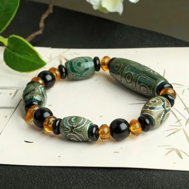 Distressed agate Tibetan bead bracelet with three-eye motifs and polished finish.