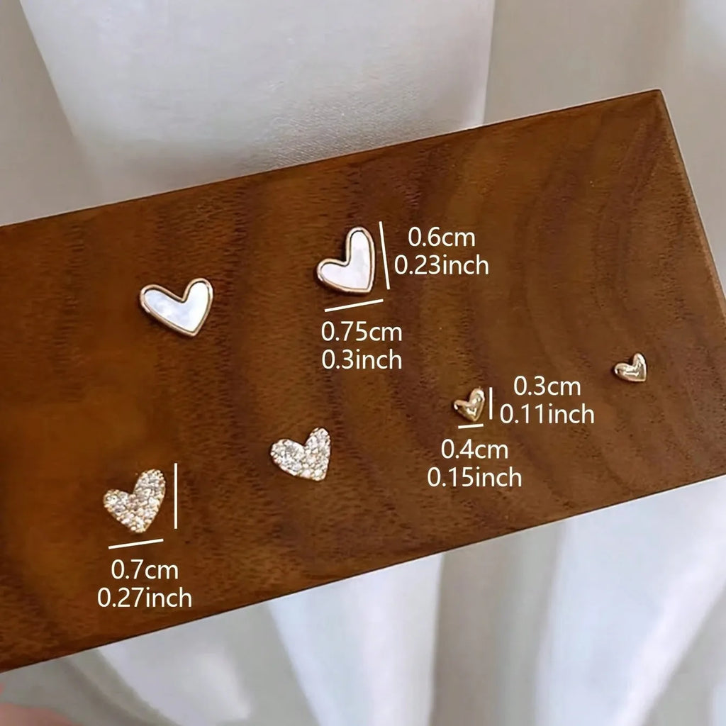 Three pairs of heart-shaped alloy earrings in gold, black, white and pink colours