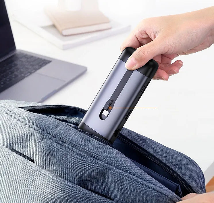 USB-C dock expansion adapter with short cable next to a laptop, showing HDMI, USB, and Ethernet ports.