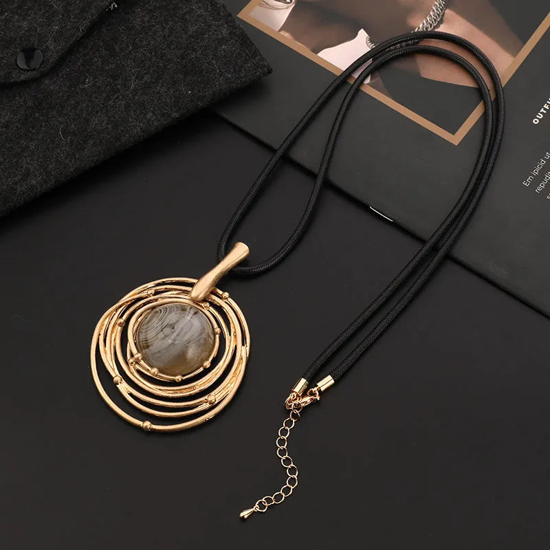 Gold geometric plaid pendant on a snakeskin-textured chain, adjustable sweater necklace.