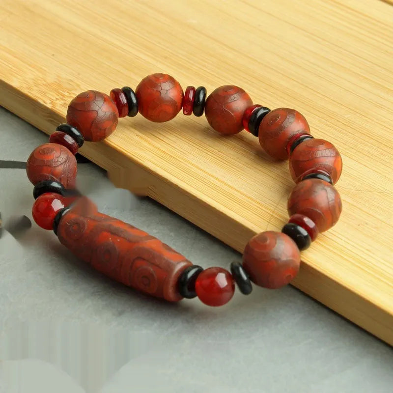Distressed agate Tibetan bead bracelet with three-eye motifs and polished finish.