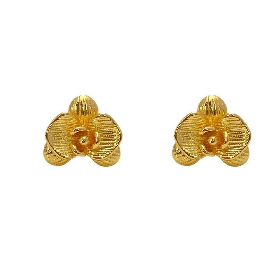 A pair of gold and silver retro-style flower earrings with petal details on a white background.