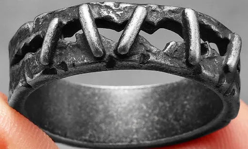 A stainless steel double ring with dark punk stitching style details, shown on a hand.