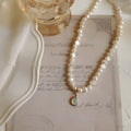 Vintage pearl necklace with geometric pendant on adjustable chain.