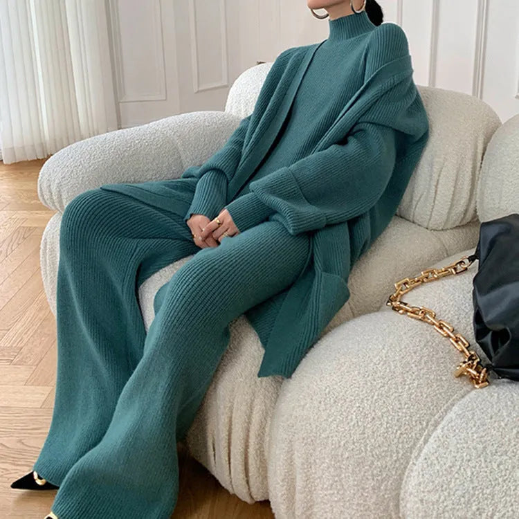 Women's knitted three-piece clothing set showing wide-leg pants, sweater and cardigan in solid colour with leather stitching details