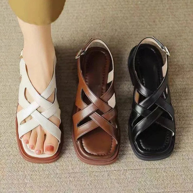 Women's glossy black patent leather sandals with a square toe and low heel on a rubber sole.