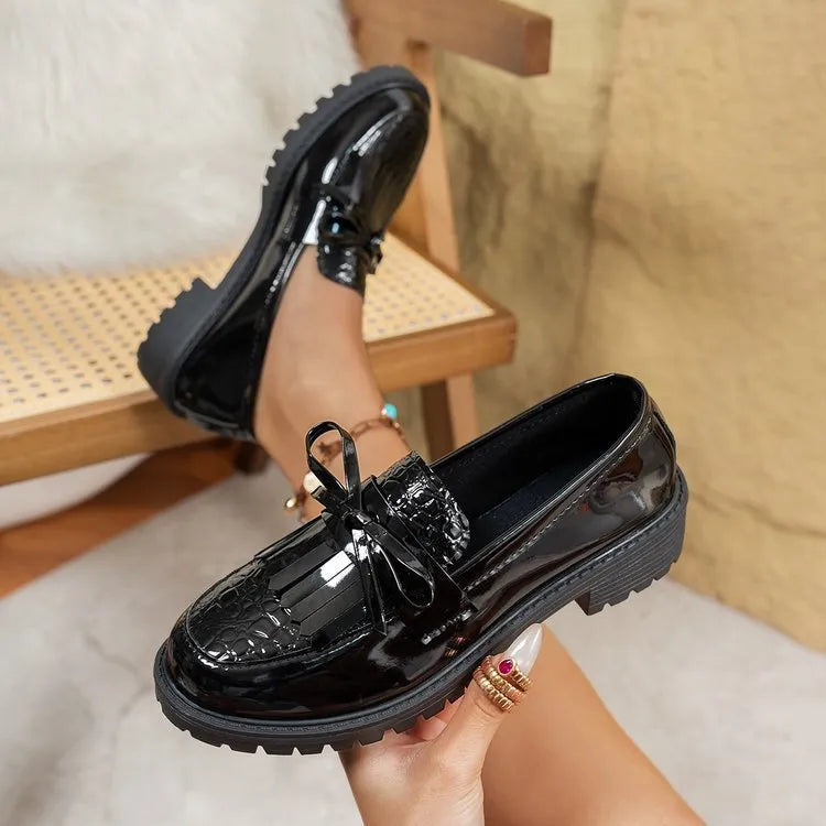 Women's brown artificial PU loafers with a black bow decoration on the vamp, shown on a white background.