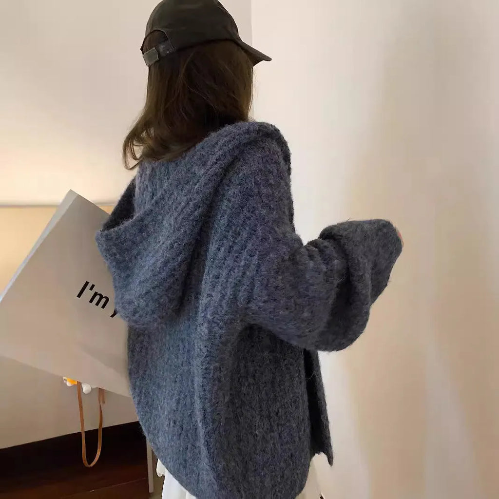 A woman's loose-fit hooded sweater cardigan in a thick fabric, shown in dark grey, brown, and milky white colour options.