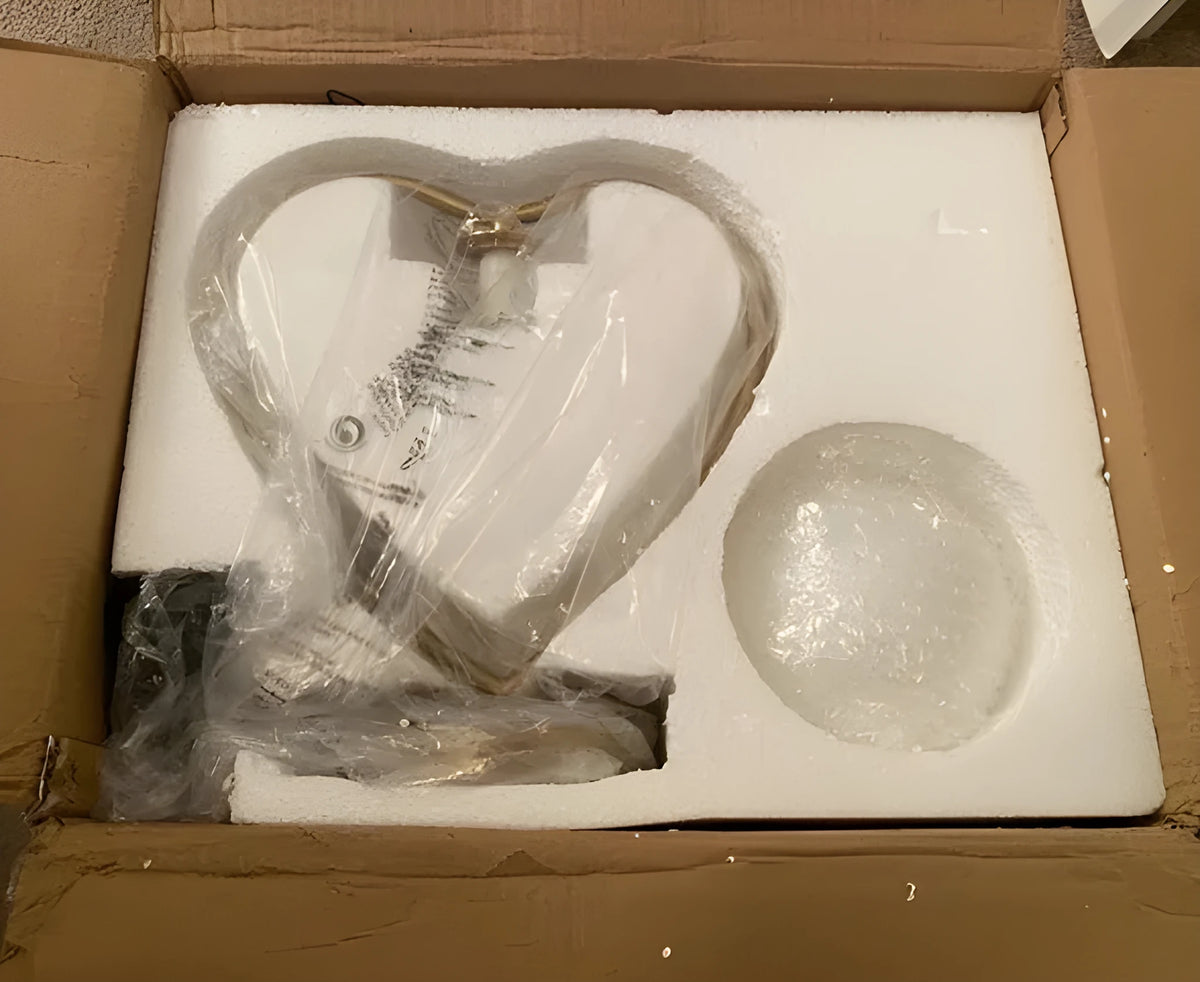 White heart shaped LED table lamp with transparent shade on a wooden surface.
