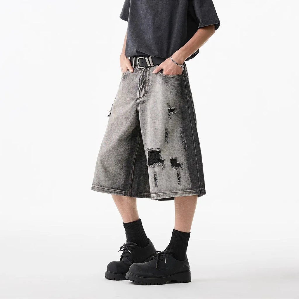 Grey women's denim shorts with a water washed finish, distressed holes, and a loose cropped fit.