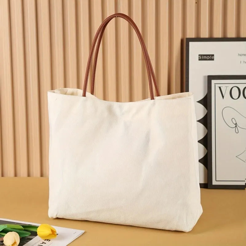 Natural beige white canvas tote bag with woven handles laid flat showing its size.