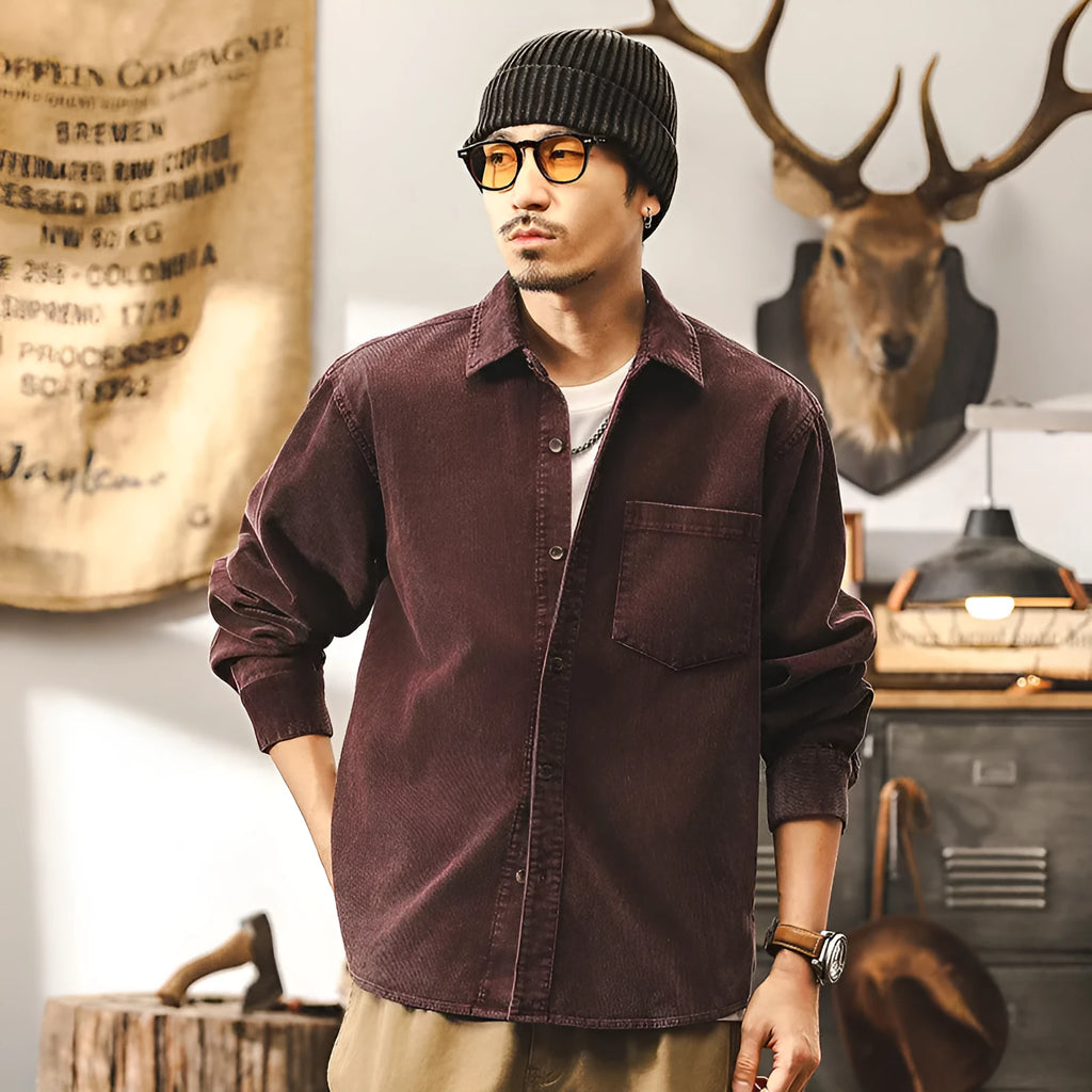 Men's black loose-fit corduroy shirt jacket with long sleeves on a hanger.