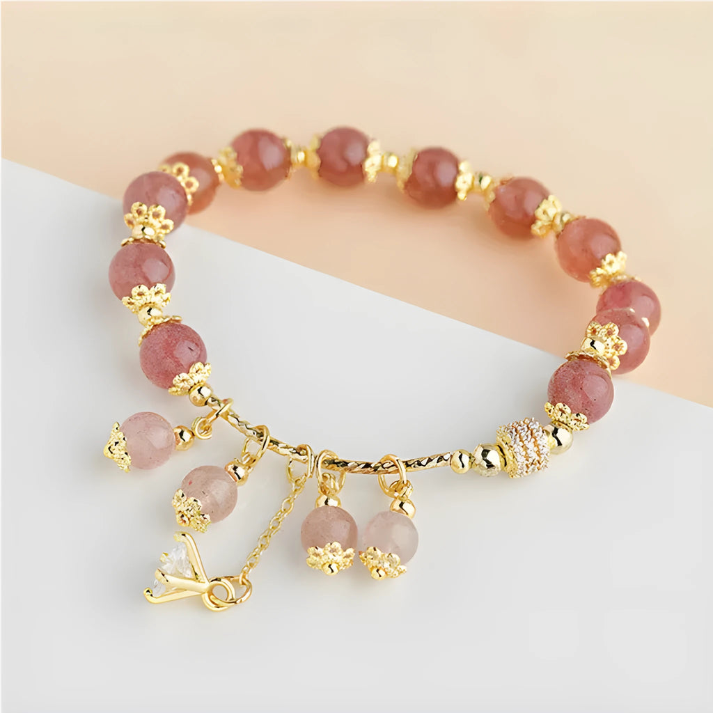 Close-up of a pink heart-shaped strawberry quartz crystal bracelet with pearl details on a wrist.