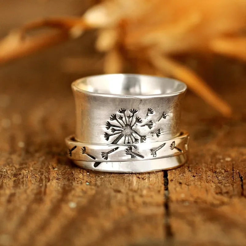 Silver coloured rotating flower fashion ring on a hand, showing adjustable band and floral design.