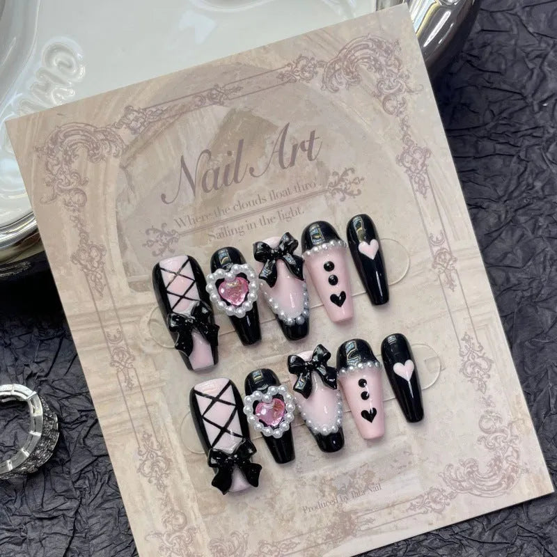 Hand-painted black and pink peach heart design on a detachable plastic manicure set with Bow and XINGX patterns.