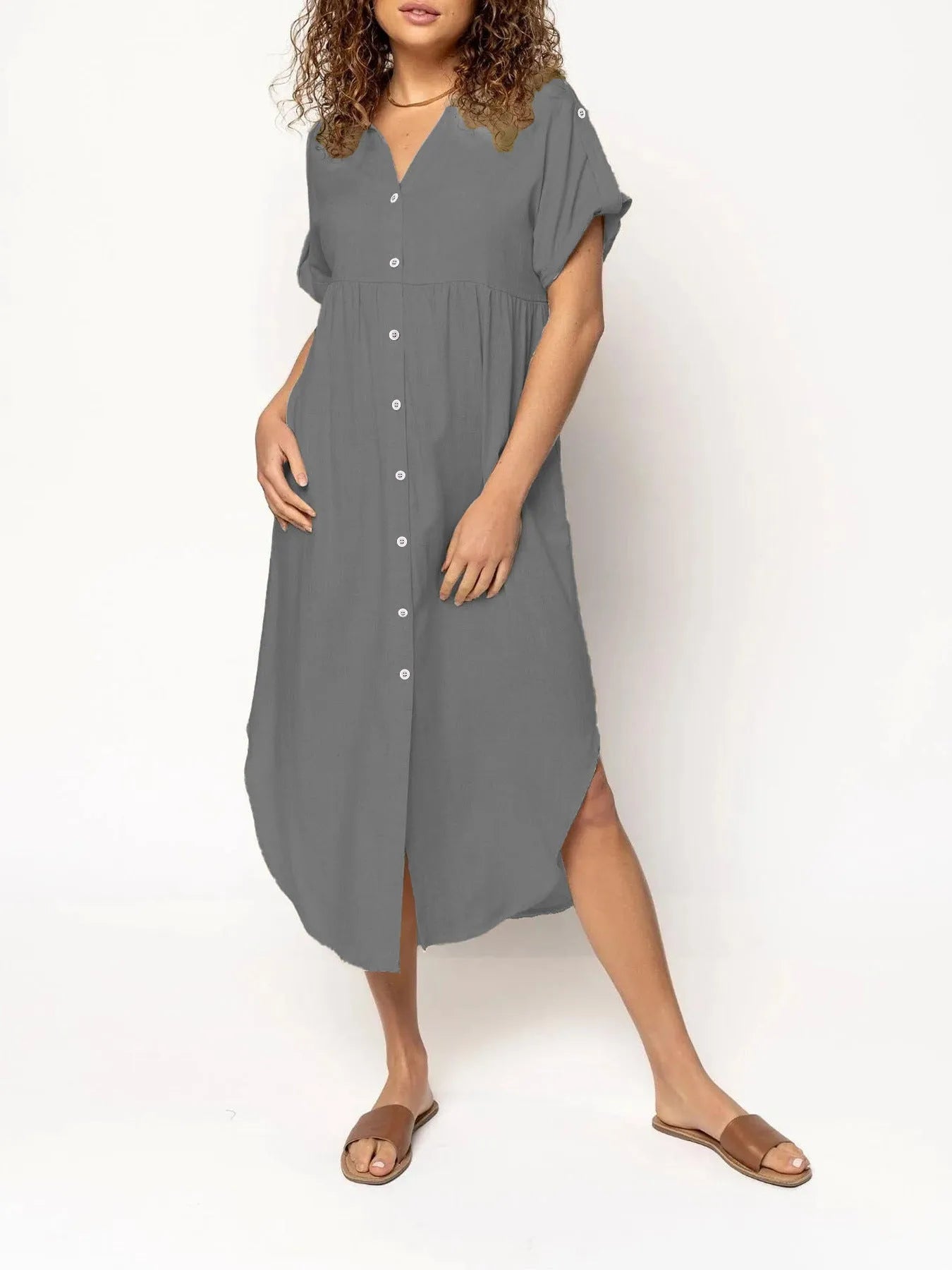 A woman wearing a loose-fitting, mid-length apricot-coloured casual dress with a button-down front.