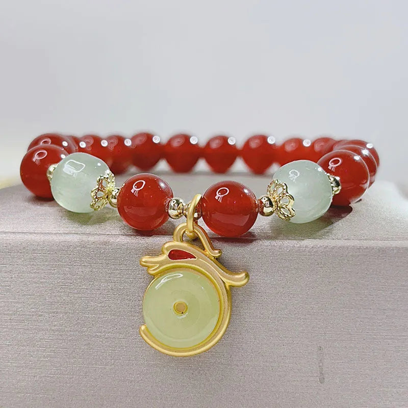 Women's red agate bracelet with manual Chinese dragon and lucky bag designs.